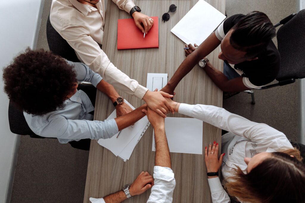 pexels-photo-5256819-5256819 Overhead view of a diverse team placing hands together in a sign of unity during a meeting.